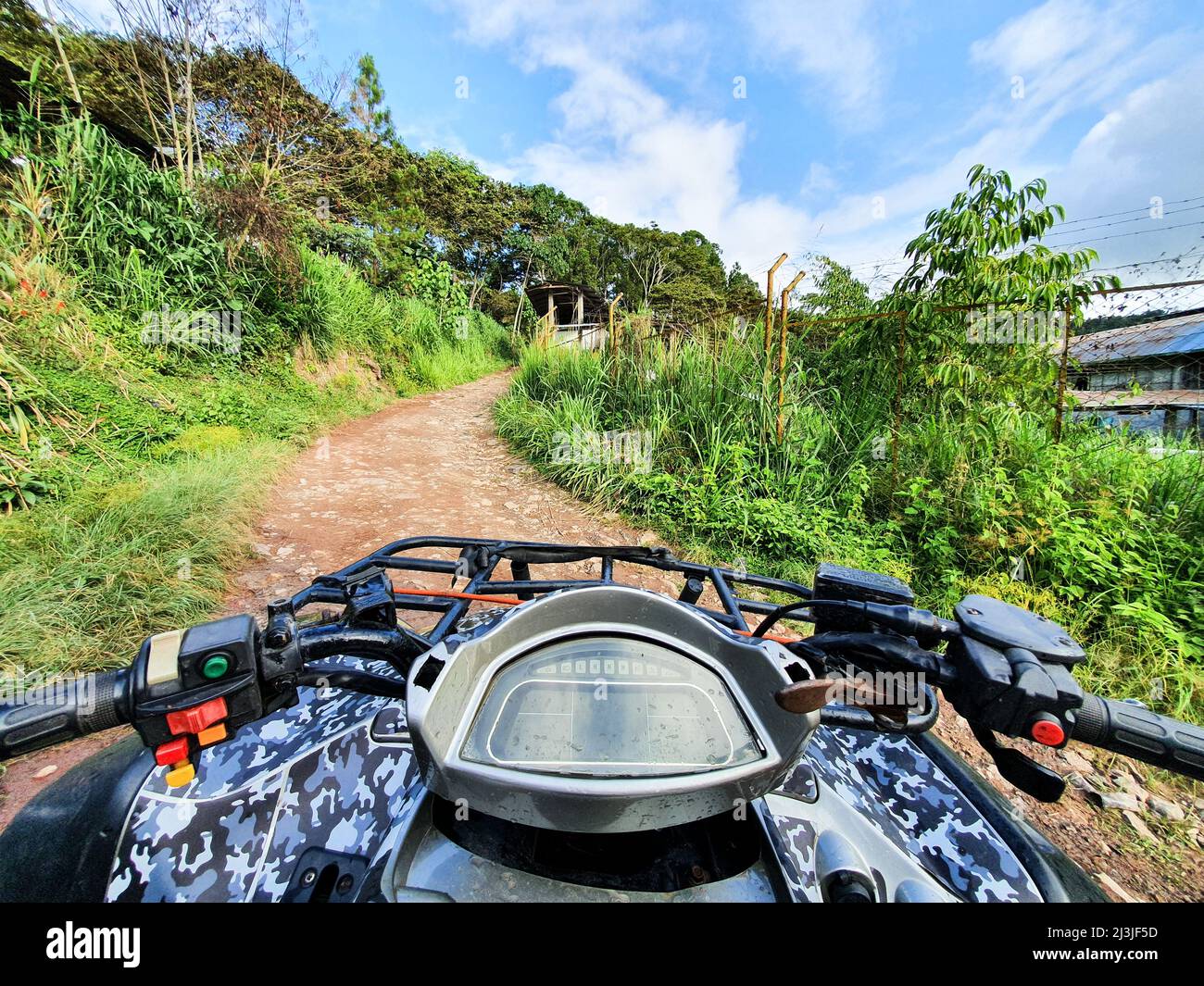 First person view in the middle of the jungle, ATV driver in the mud. Adventure trip in the forest. Soft focus. Man on quadbike race over rough terrain in the forest on a hot summer day Stock Photo