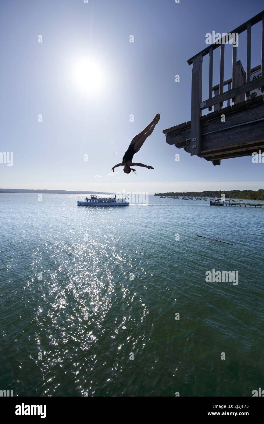 Woman jumping from diving tower at lido Utting am Ammersee, Bavaria, Germany Stock Photo