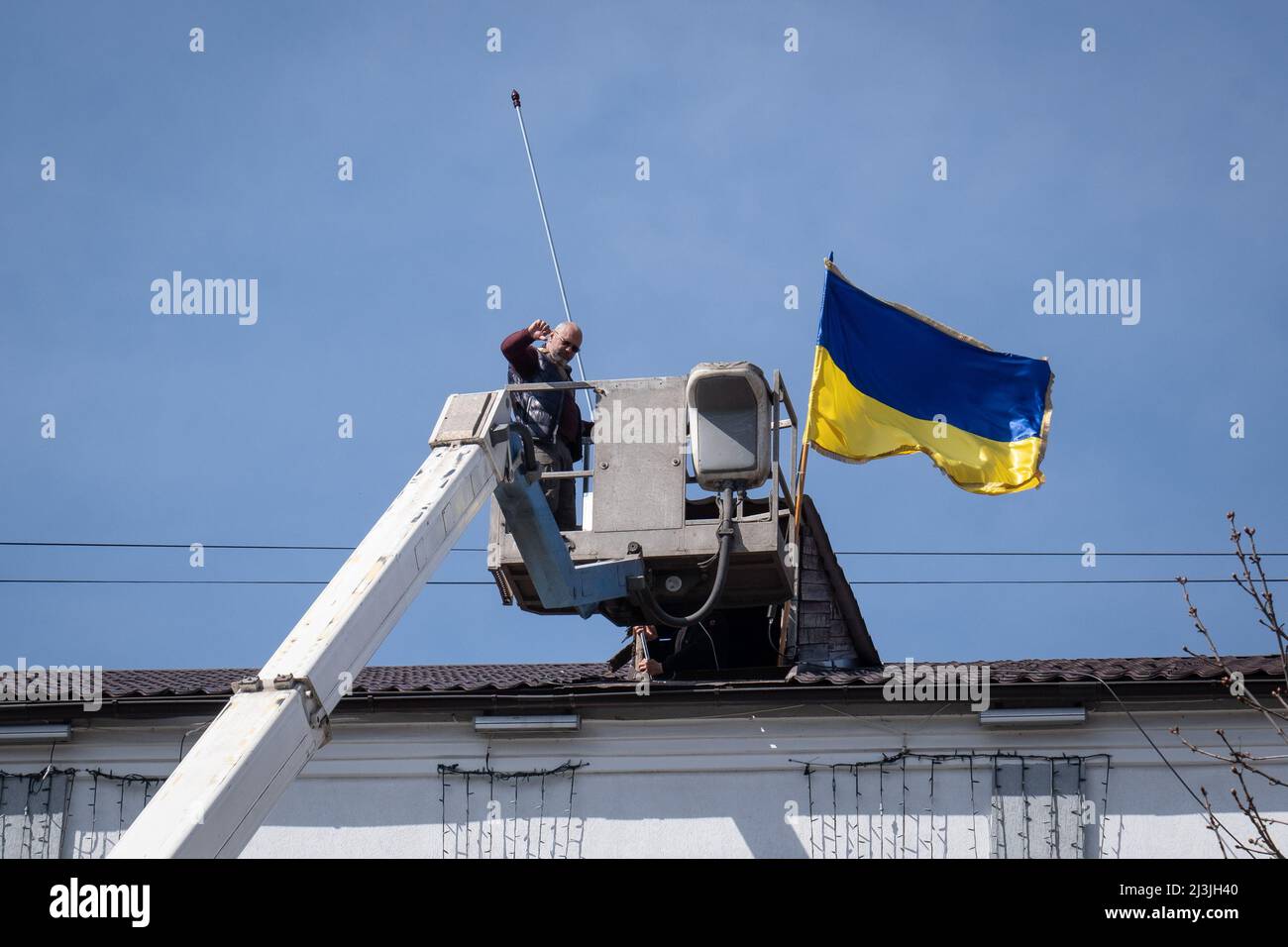Bucha, Ukraine. 07th Apr, 2022. A man raising up the Ukrainian National Flag in Bucha City Council at Bucha, Kyiv Oblast. Following the recapture of Bucha by the Ukrainian forces, the city was devastated under intense fighting and shelling, as the Russian forces are said to have killed hundreds of civilians in the town. (Photo by Alex Chan Tsz Yuk/SOPA Images/Sipa USA) Credit: Sipa USA/Alamy Live News Stock Photo