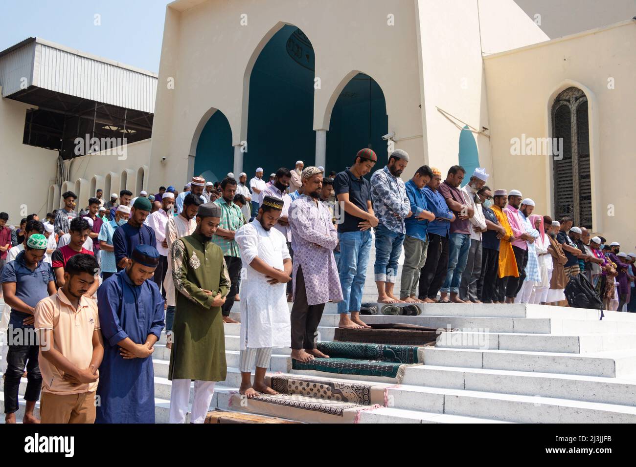 Non Exclusive: DHAKA, BANGLADESH - APRIL 8, 2022: Muslim devotees offer Jummah prayer during the holy month of Ramadan outside of the  Baitul Mukarram Stock Photo
