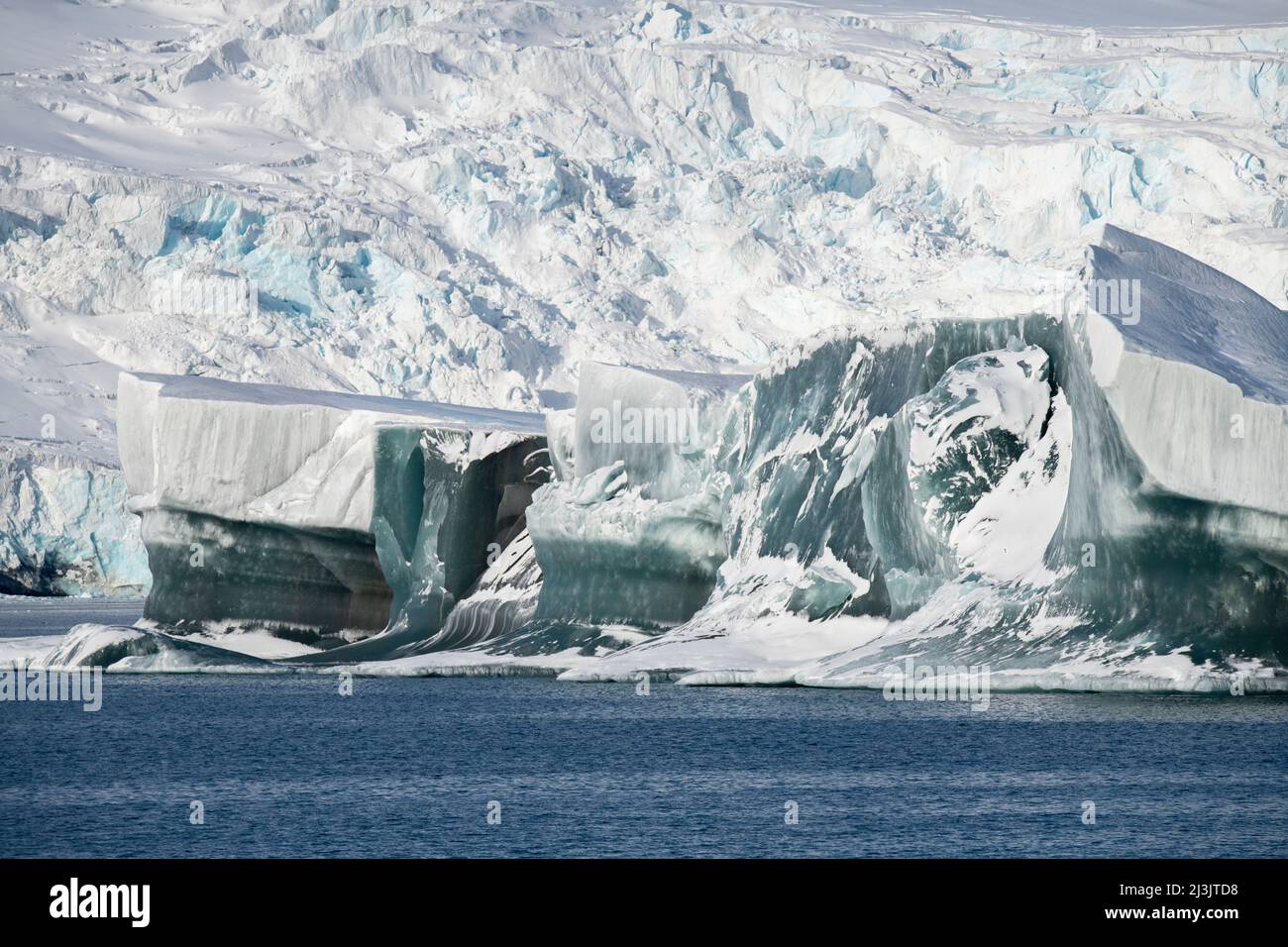 Antarctica, Southern Ocean, South Orkney Islands, Coronation Island, Iceberg Bay. Rare large 'jade ice' iceberg with Sunshine Glacier in the distance. Stock Photo