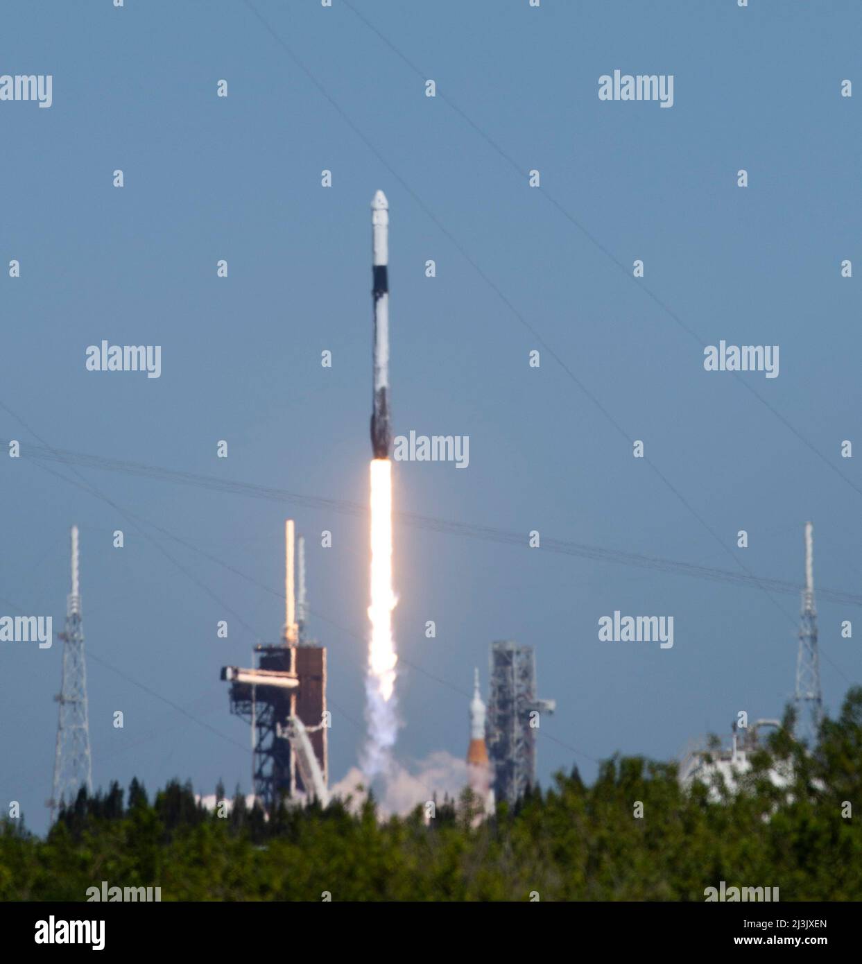 Florida, USA. 08th Apr, 2022. NASA's Space Launch System (SLS) rocket with the Orion spacecraft aboard is seen atop a mobile launcher at Launch Complex 39B, right, as a SpaceX Falcon 9 rocket carrying the company's Crew Dragon spacecraft is launched on Axiom Mission 1 (Ax-1) to the International Space Station with Commander Michael López-Alegría of Spain and the United States, Pilot Larry Connor of the United States, and Mission Specialists Eytan Stibbe of Israel, and Mark Pathy of Canada aboard, Friday, April 8, 2022, at NASA's Kennedy Space Center in Florida. The Ax-1 mission is the first pr Stock Photo