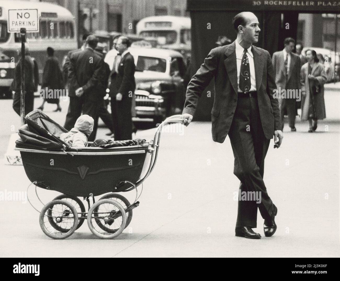 Man standing on Sidewalk with one hand on baby carriage, New York City, New York, USA, Angelo Rizzuto, Anthony Angel Collection, November 1953 Stock Photo