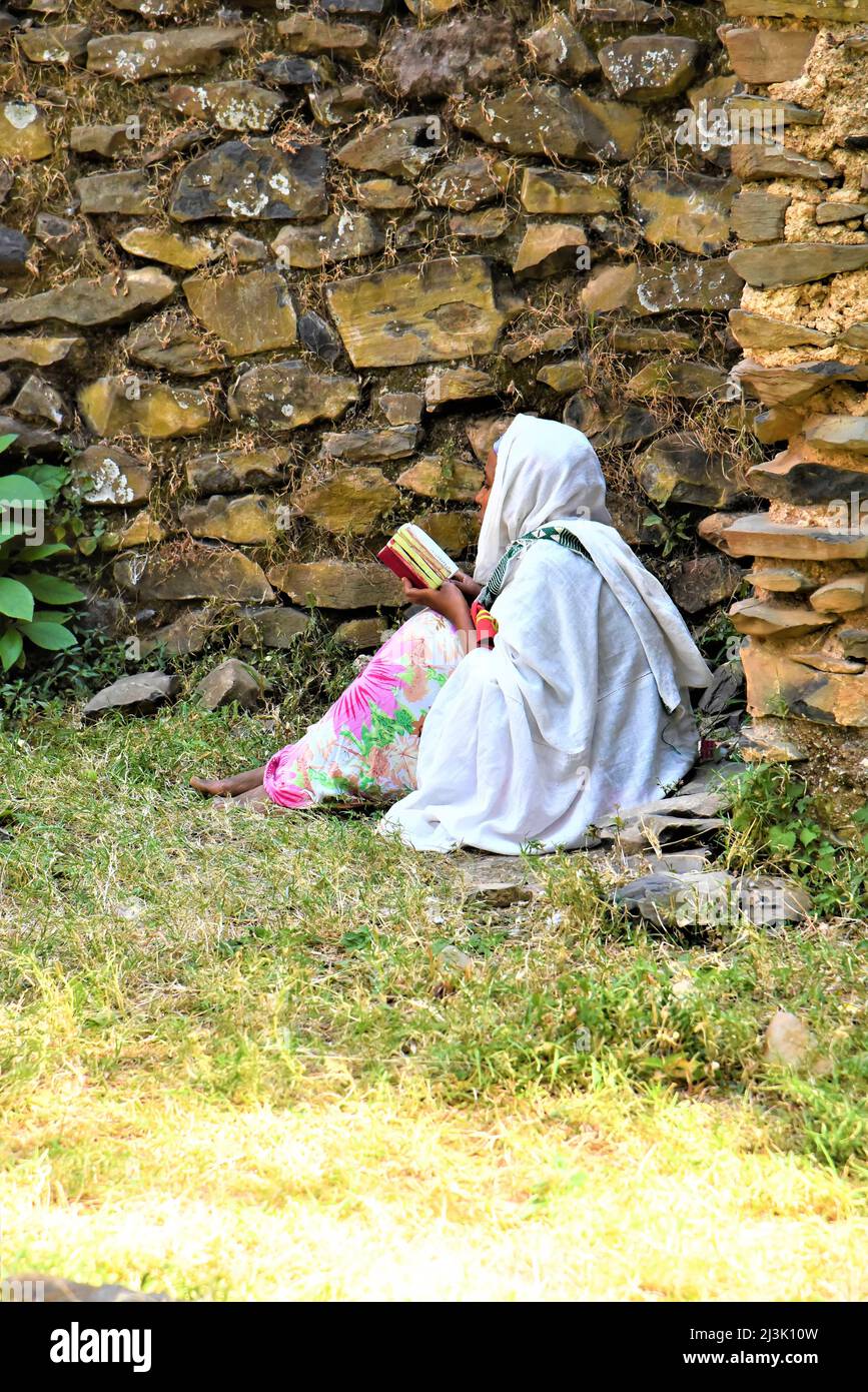 Woman reading scripture on the ground outside Debre Birhan Selassie Church in rural Ethiopia; Ethiopia Stock Photo