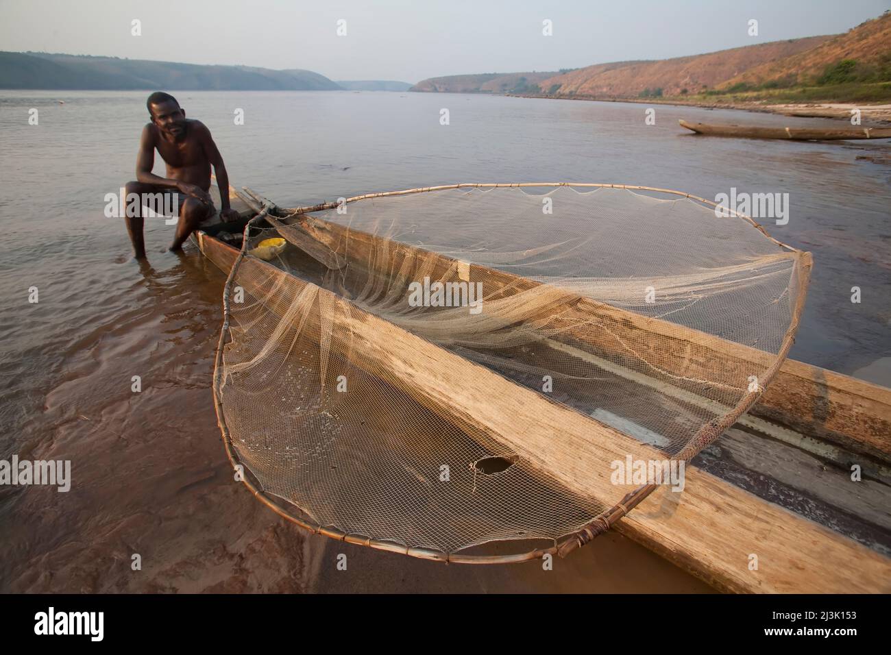 A Congolese fisherman in a traditional pirogue or dug out canoe.; Lower