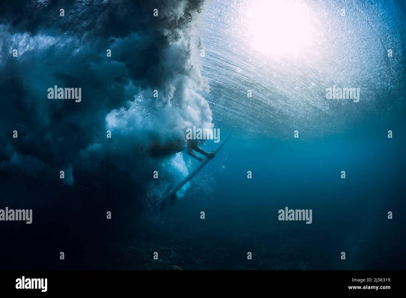 Surfer woman with surfboard dive underwater with under ocean wave Stock