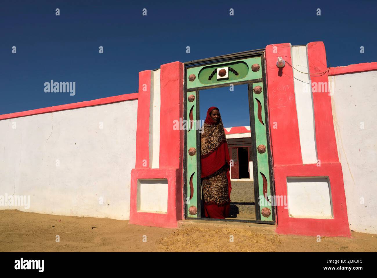 Nubian villagers pose outside freshly painted walls.; Sudan, Africa. Stock Photo