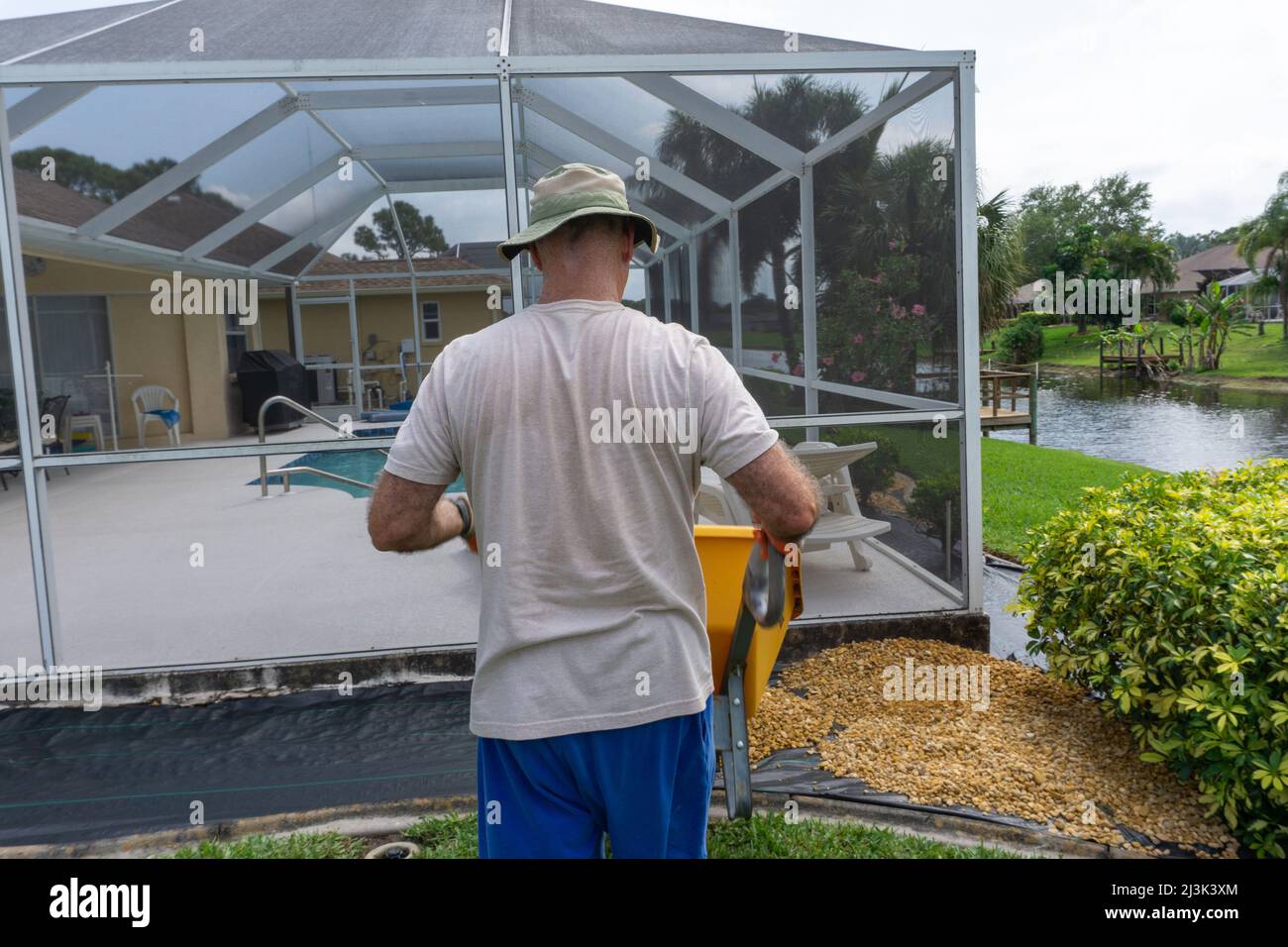 Retiree gardening in Florida drives wheelbarrow Stock Photo