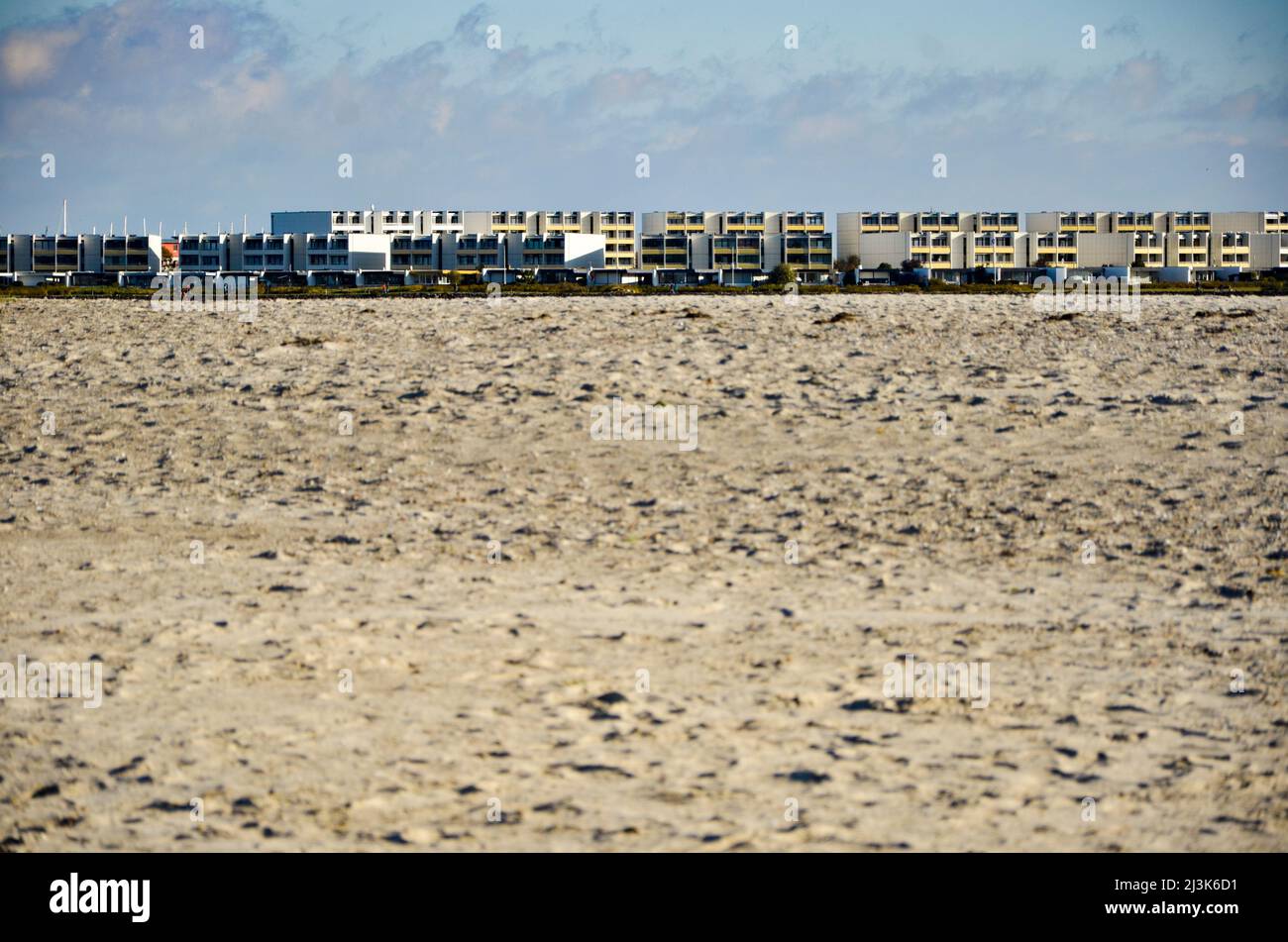 extensive sandy beach with holiday apartments on the horizon Stock Photo