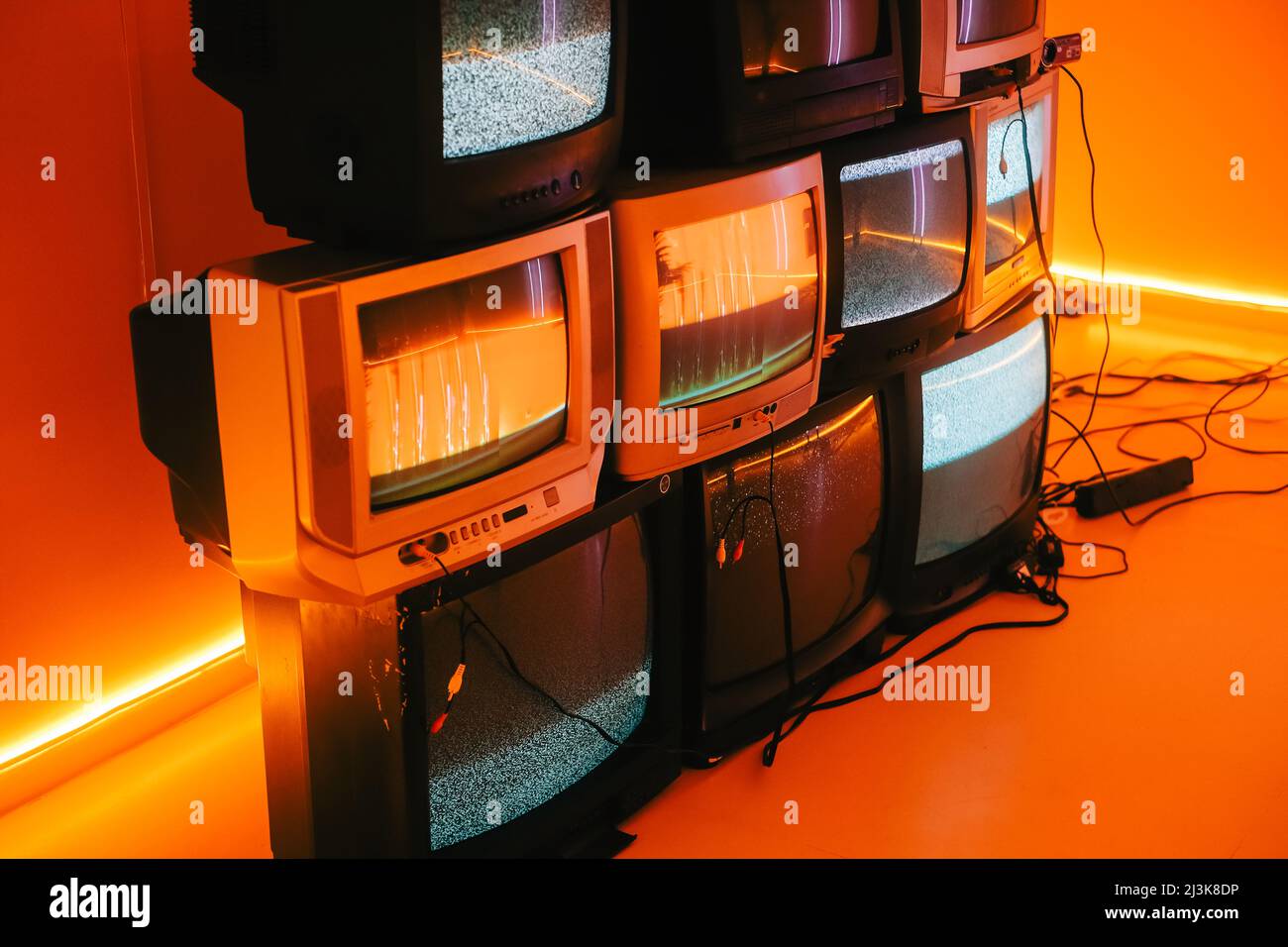 Old vintage tvs on a floor in a room with colored neon light. Stock Photo