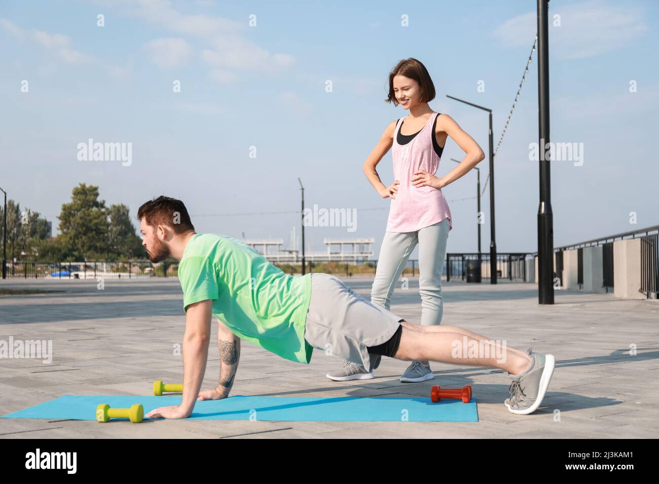 Sporty young man doing push-up with his girlfriend outdoors Stock Photo ...