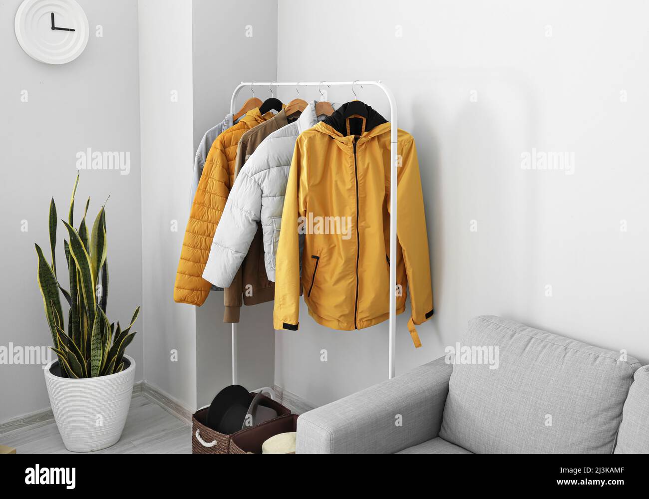 Rack with warm jackets near light wall in living room Stock Photo