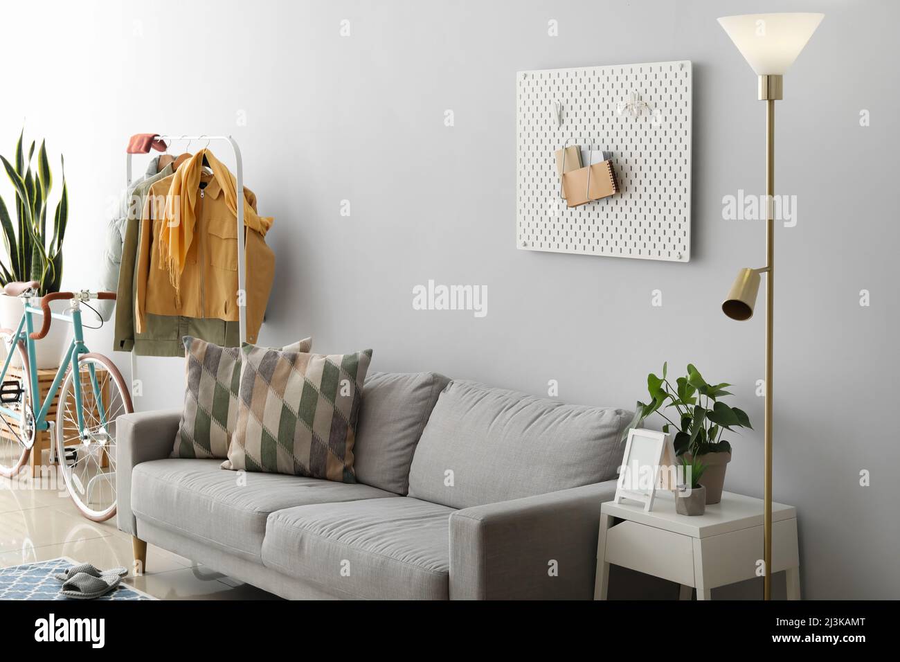 Interior of light living room with sofa, jackets and bicycle Stock Photo