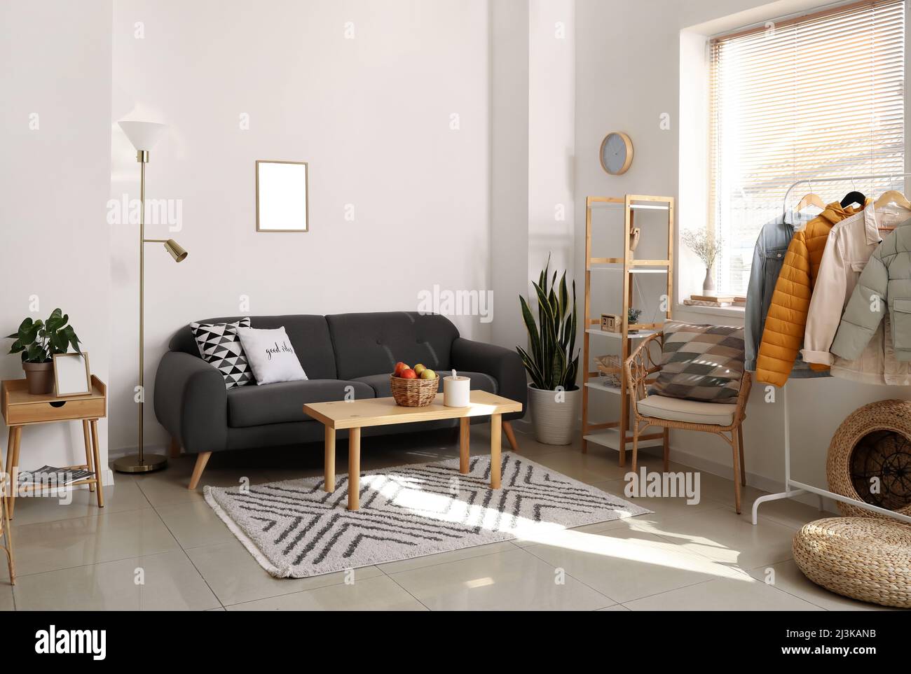 Interior of light room with black sofa and warm jackets Stock Photo