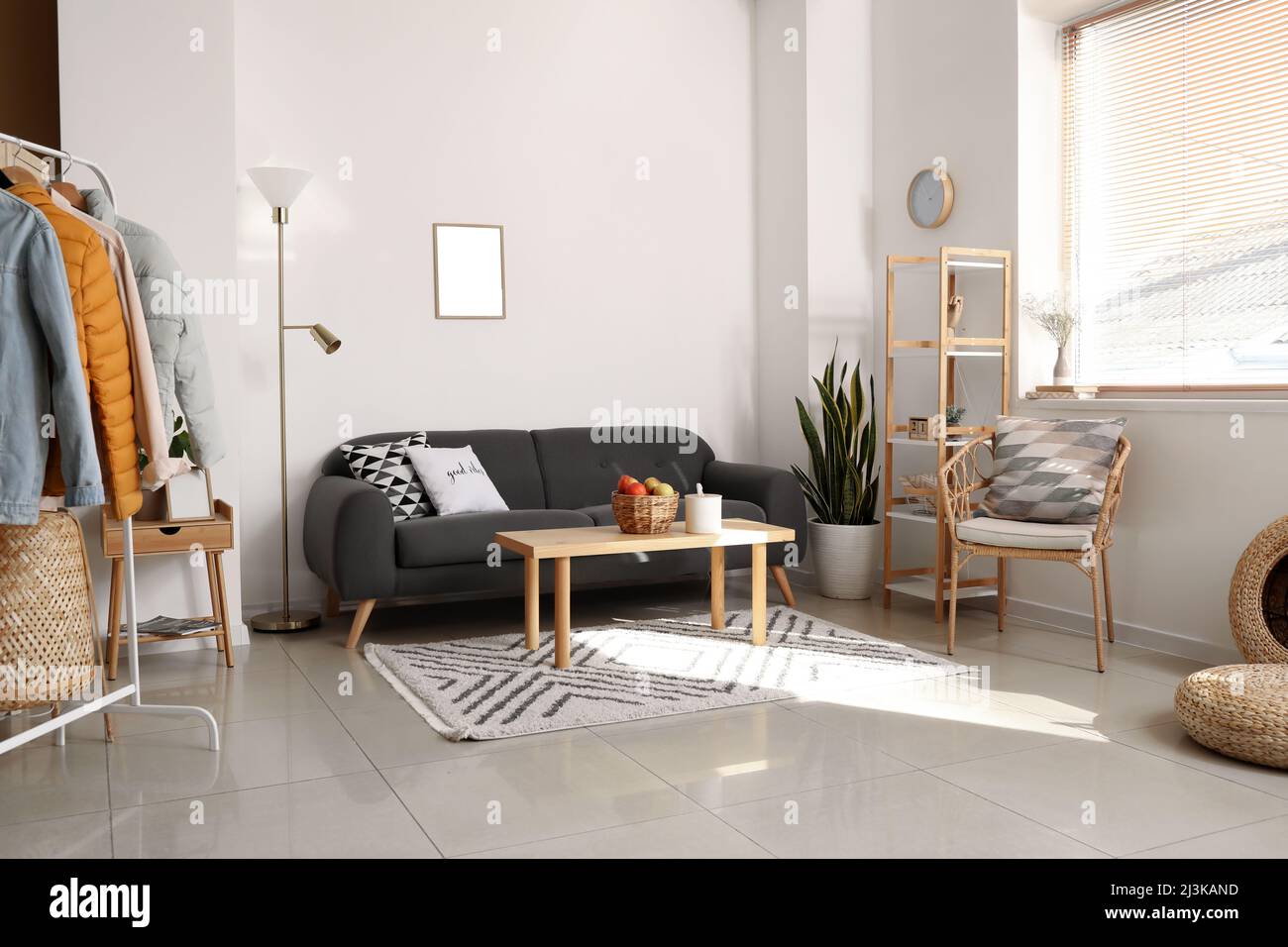 Interior of light room with black sofa and warm jackets Stock Photo