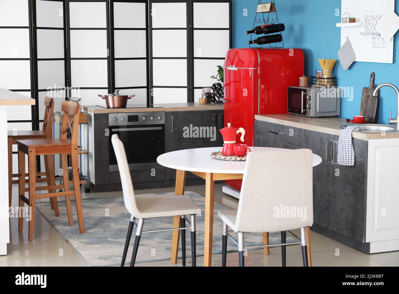 Interior of stylish kitchen with red fridge, counters and dining table ...