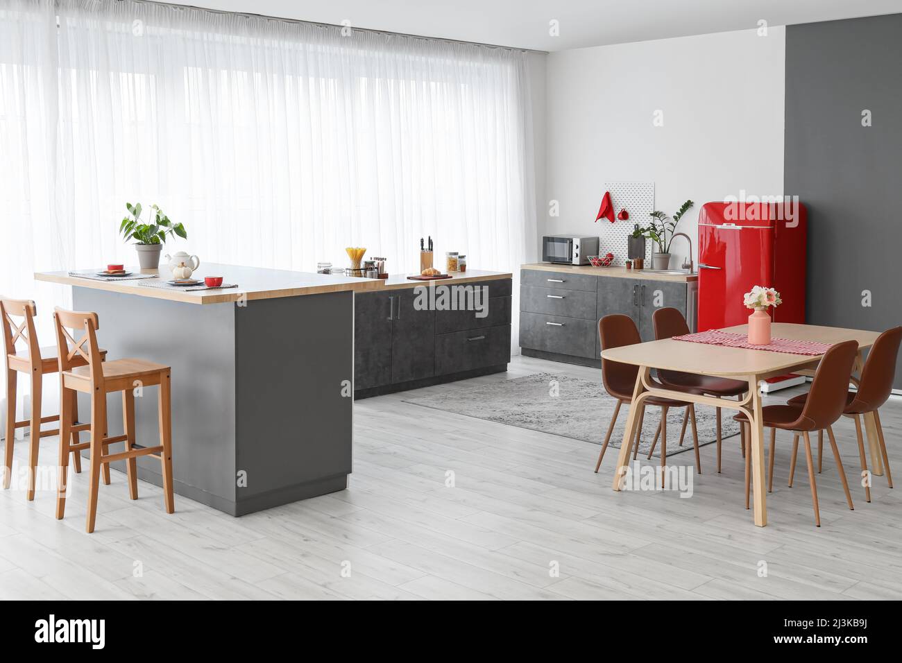 Interior of modern kitchen with red fridge, counters and dining table ...