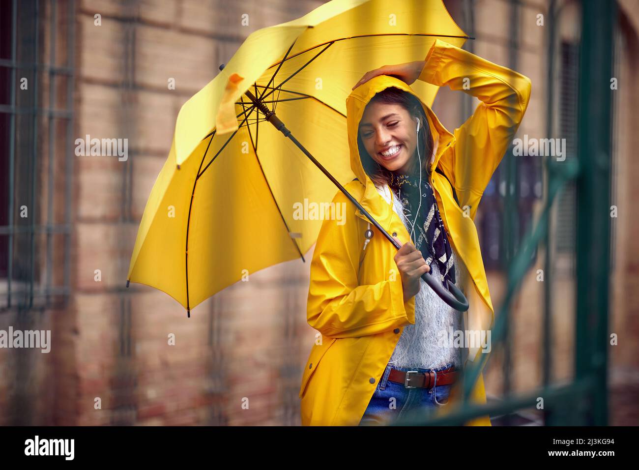 Young smiling woman with yellow umbrella standing outdoor Stock Photo ...