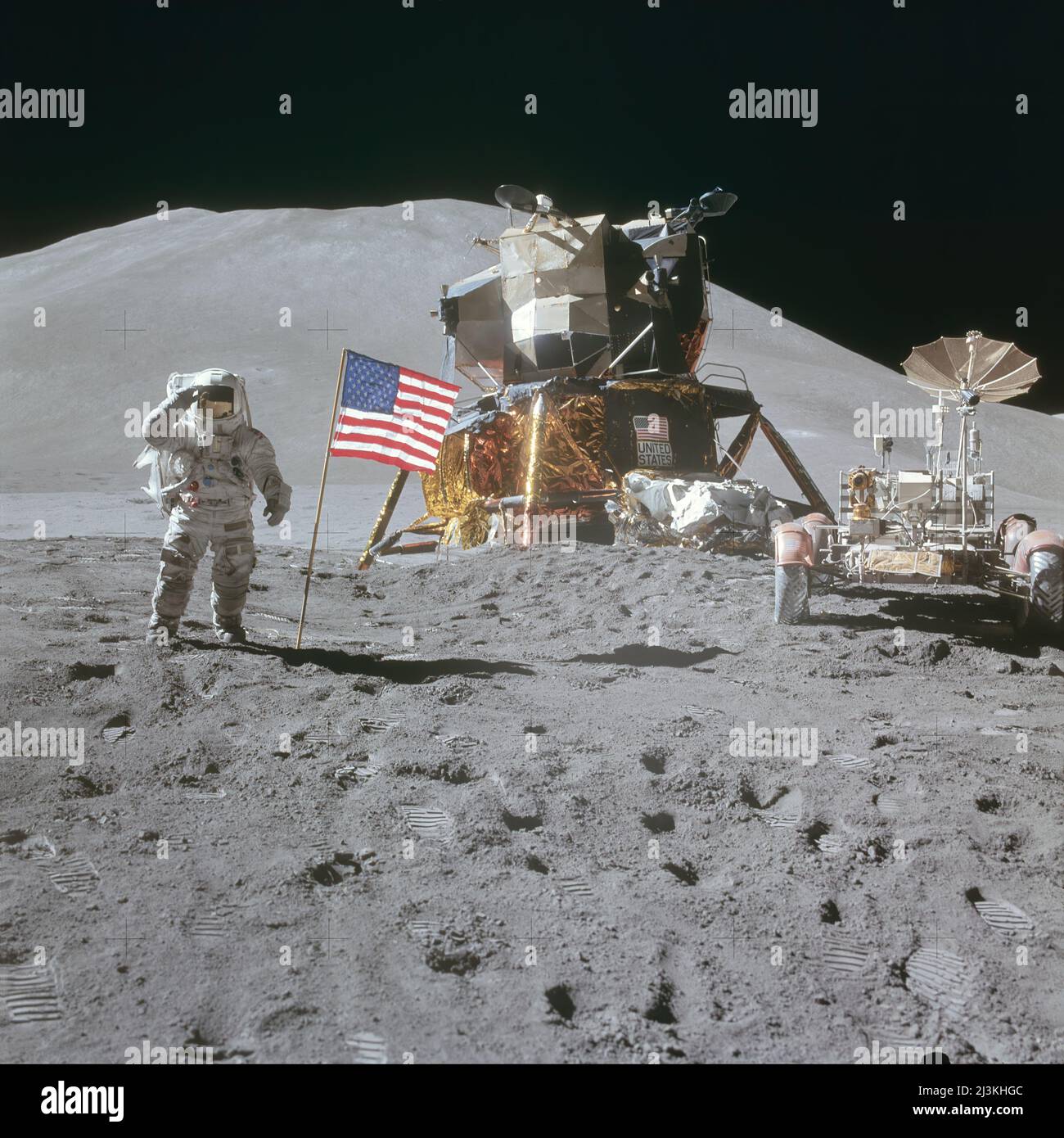 Astronaut James Irwin, lunar module pilot, saluting American flag during the Apollo 15 lunar surface extravehicular activity (EVA) at the Hadley-Apennine landing site. The Lunar Module (LM) 'Falcon' is in the center. On the right is the Lunar Roving Vehicle (LRV). The mountain Hadley Delta in the background rises approximately 4,000 meters (about 13,124 feet) above the plain. Stock Photo