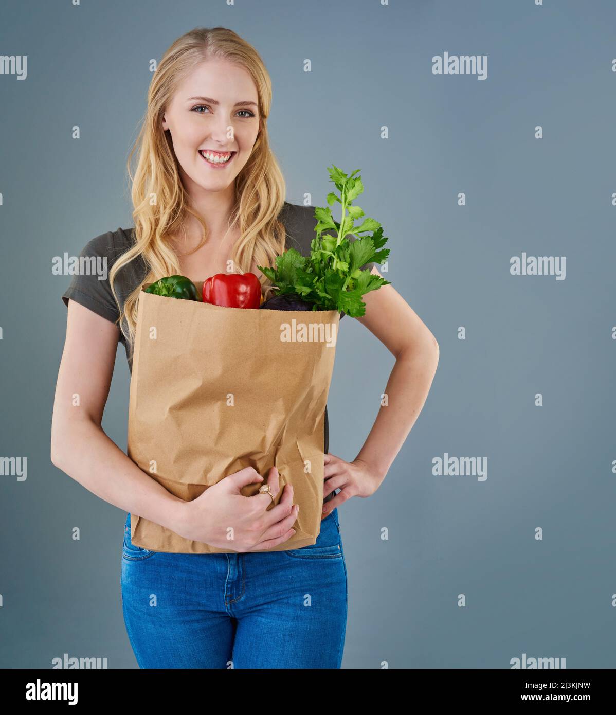 Eating healthy and looking great. Cropped studio shot of a young woman holding a paper bag full of vegetables. Stock Photo