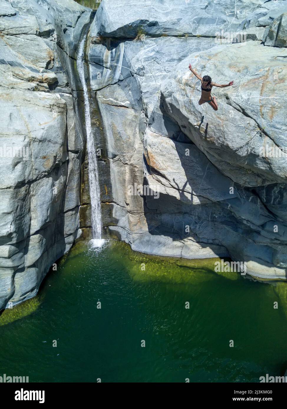 A woman jumps into a pool of water off of a cliff Stock Photo - Alamy