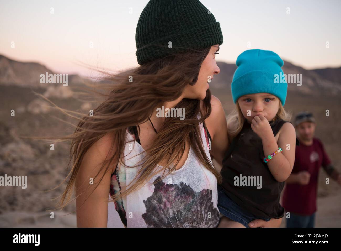 Hikers and a child on top of Cyclops Rock in Joshua Tree National Park at sunset. Stock Photo