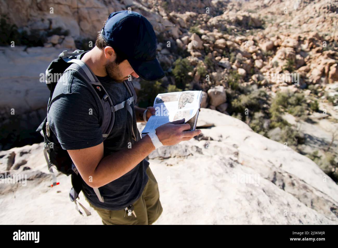 A man looks through the guidebook to Joshua Tree National Park in search of a remote climb. Stock Photo