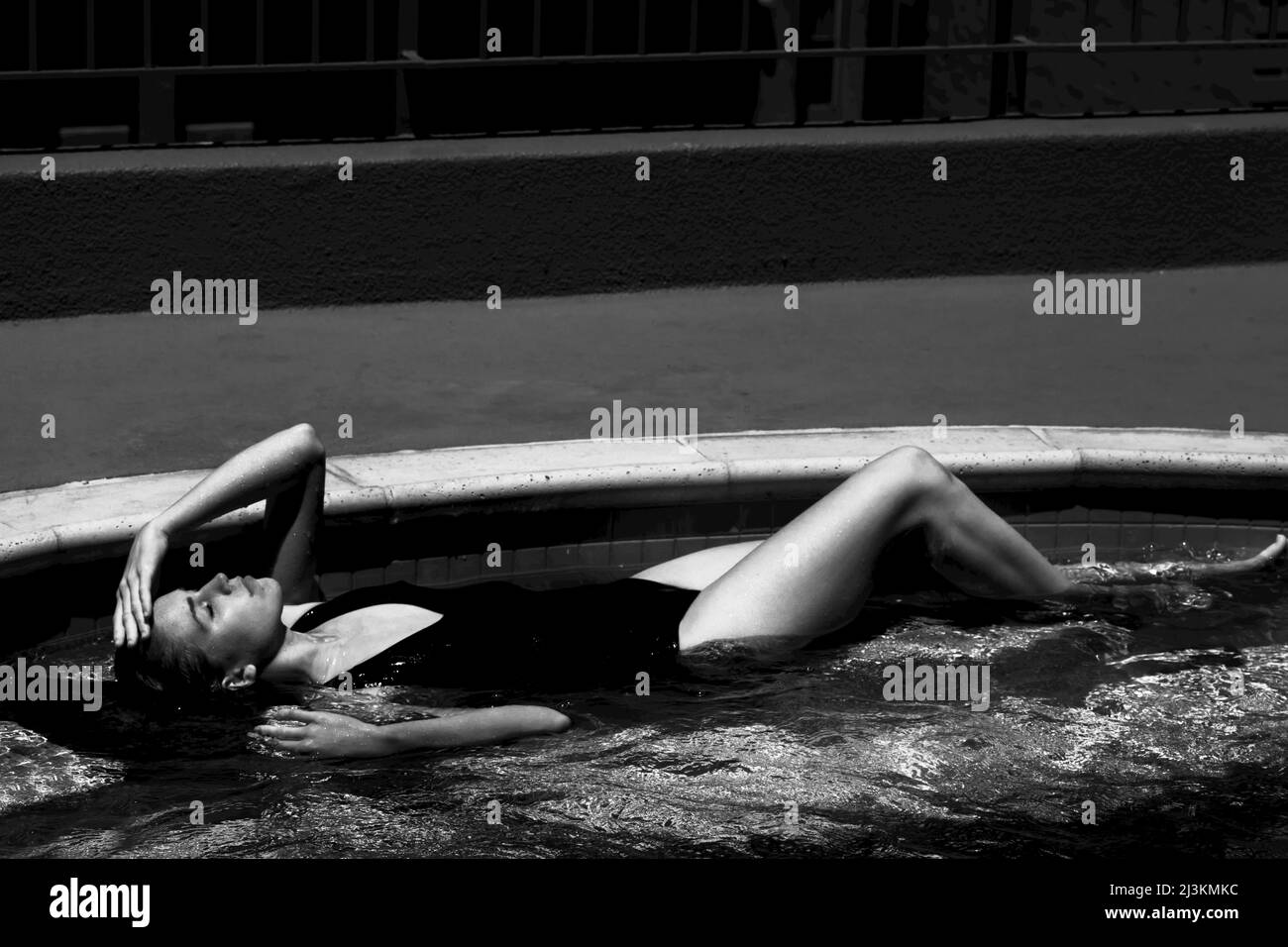 A woman relaxes in a swimming pool. Stock Photo