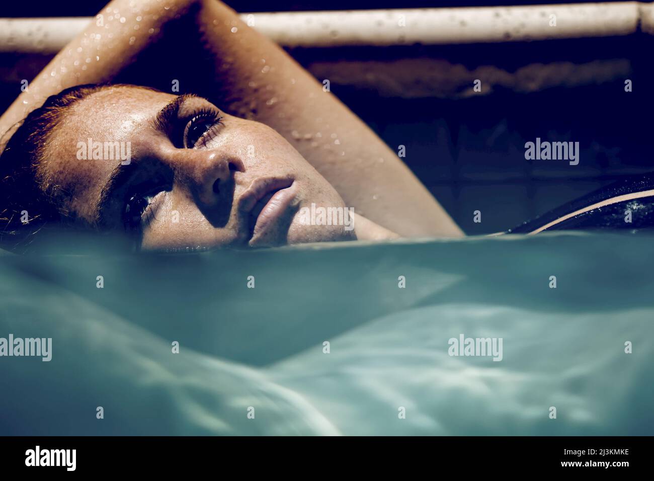 A woman relaxes in a swimming pool. Stock Photo