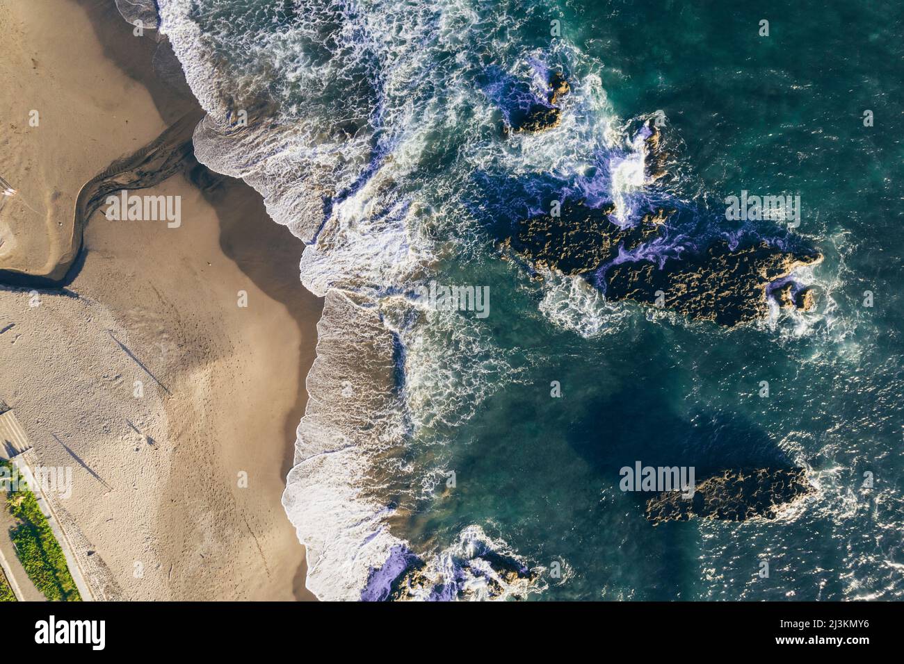 Drone aerial view of beach and sea surf on the shoreline at Batu Bolong