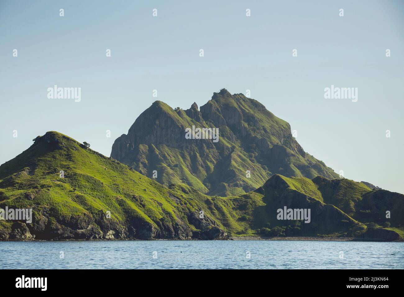 Rugged landforms covered in green foliage along the ocean coastline ...