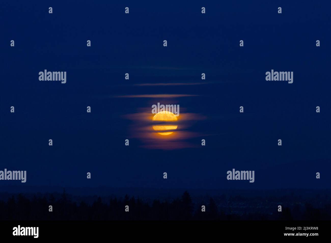 Moody imagery of glowing moon through clouds; Surrey, British Columbia, Canada Stock Photo