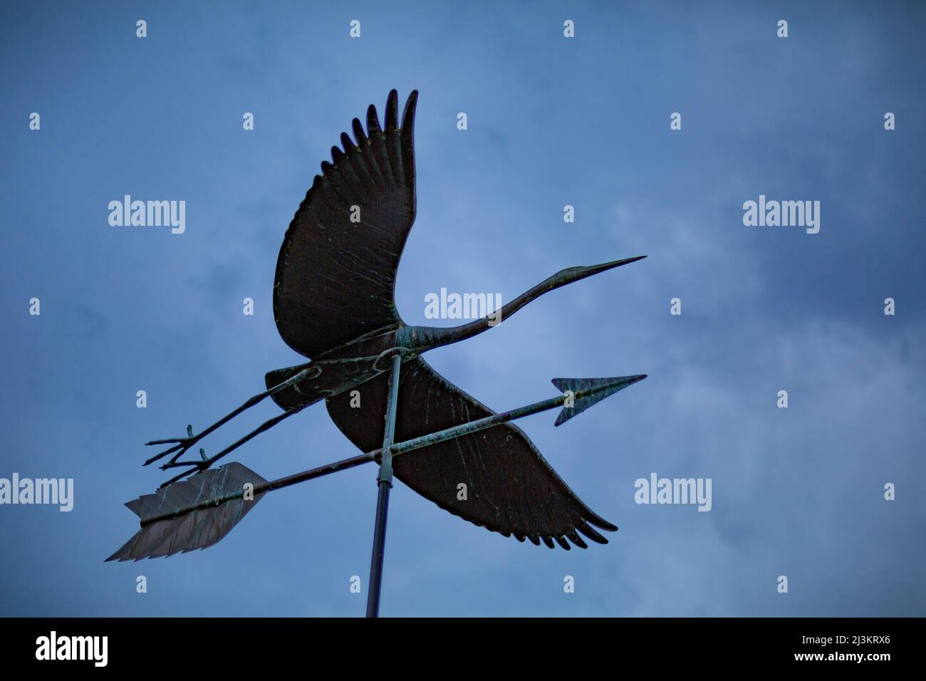 Close-up low angle view of a metal wind vane in bird likeness against a cloudy sky; Vancouver, British Columbia, Canada Stock Photo