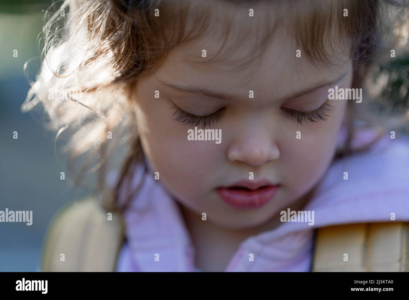 Close-up portrait of a preschooler girl with long eyelashes, looking down; North Vancouver, British Columbia, Canada Stock Photo