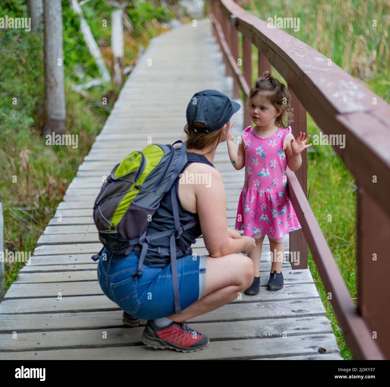 Mother and young daughter hold hands and walk down a trail on a hike together in Smuggler Cove Marine Provincial Park along the Sunshine Coast of B... Stock Photo