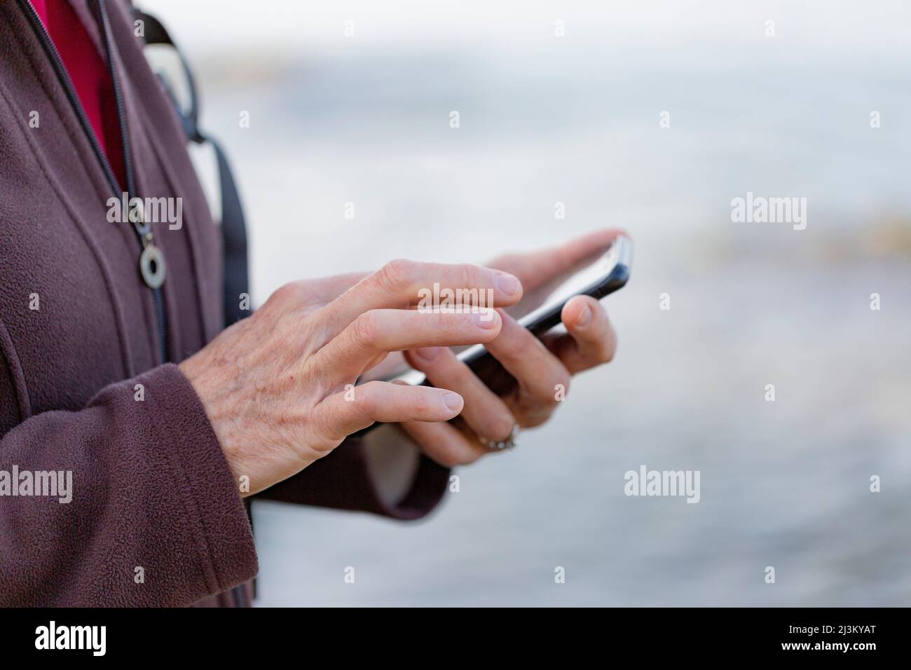 Close-up detail of a woman's hands using a smart phone while hiking; British Columbia, Canada Stock Photo
