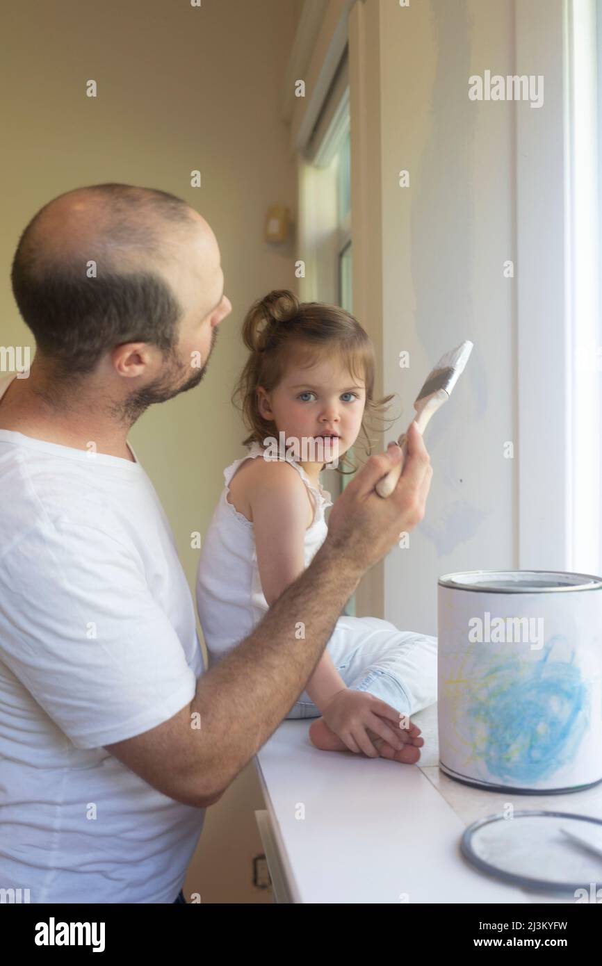 Father with young daughter painting walls at home; North Vancouver, British Columbia, Canada Stock Photo