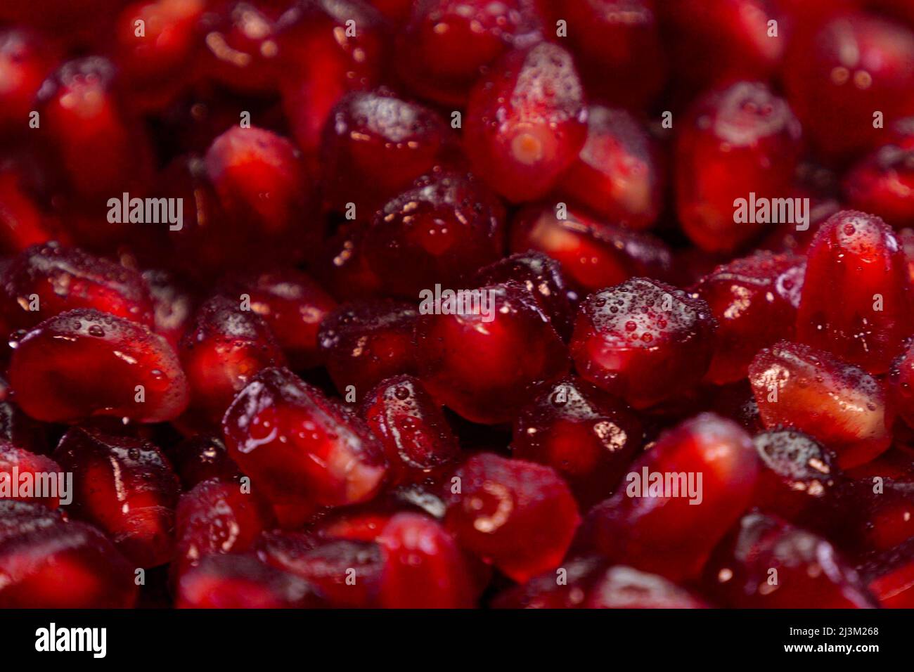 Heap of pomegranate grains close up. Red seeds of grenade macro view. Stock Photo