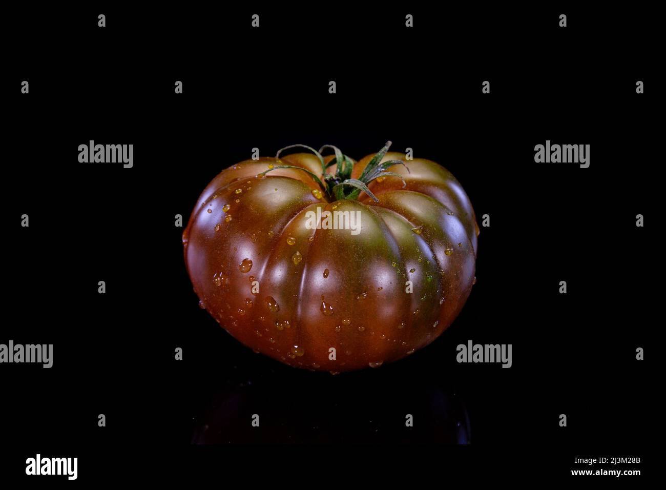 Chocolate tomatoes on a black background. Fresh and firm tomato. Restaurant, groceries store or agriculture promo. Stock Photo
