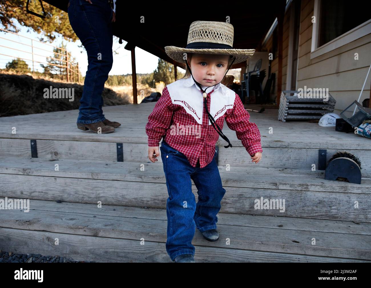 Young cowgirl heads to the barn to watch the horses; Prineville, Oregon