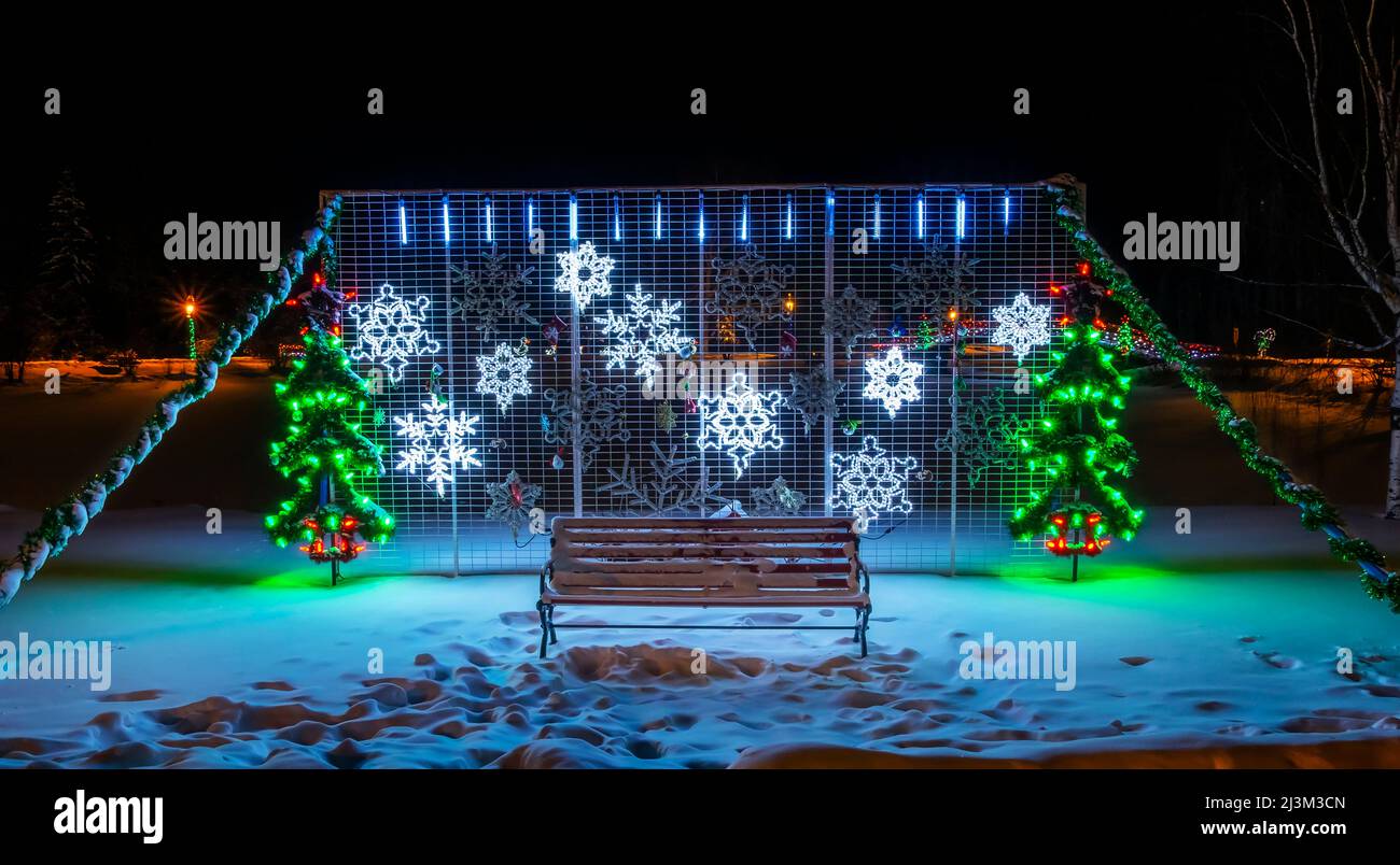 Christmas lights illuminate a decorative display at night in a snowy