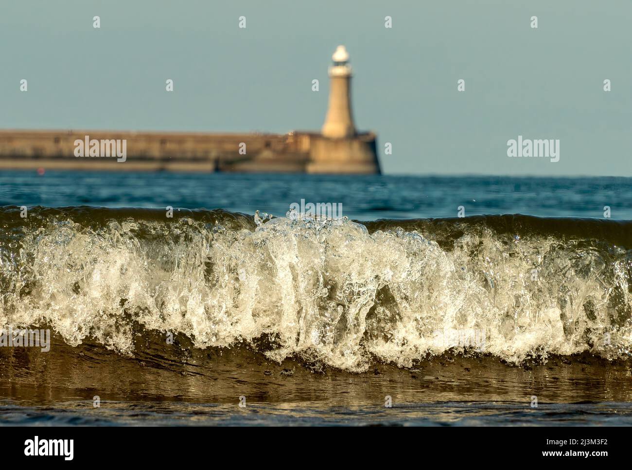 Surf washing up on beach in the foreground with Tynemouth North Pier light and pier in the background; South Shields, Tyne and Wear, England Stock Photo