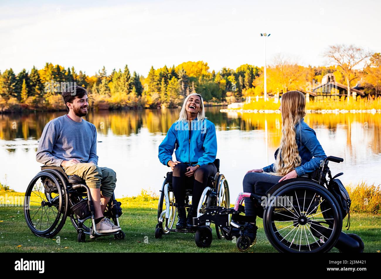 Group of three young paraplegics in their wheelchairs visiting together in a park on a beautiful