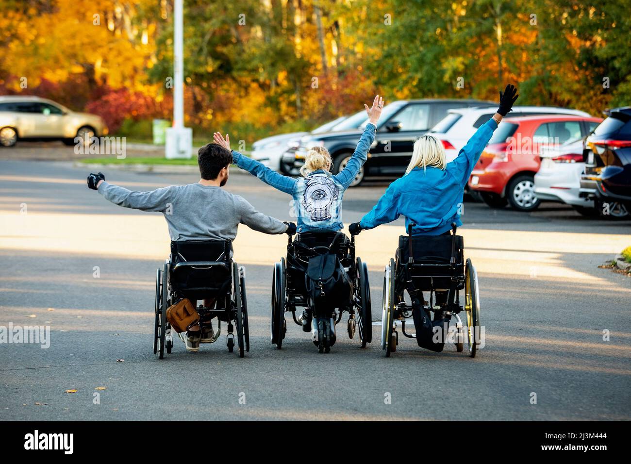 Three young paraplegics in their wheelchairs going through a parking