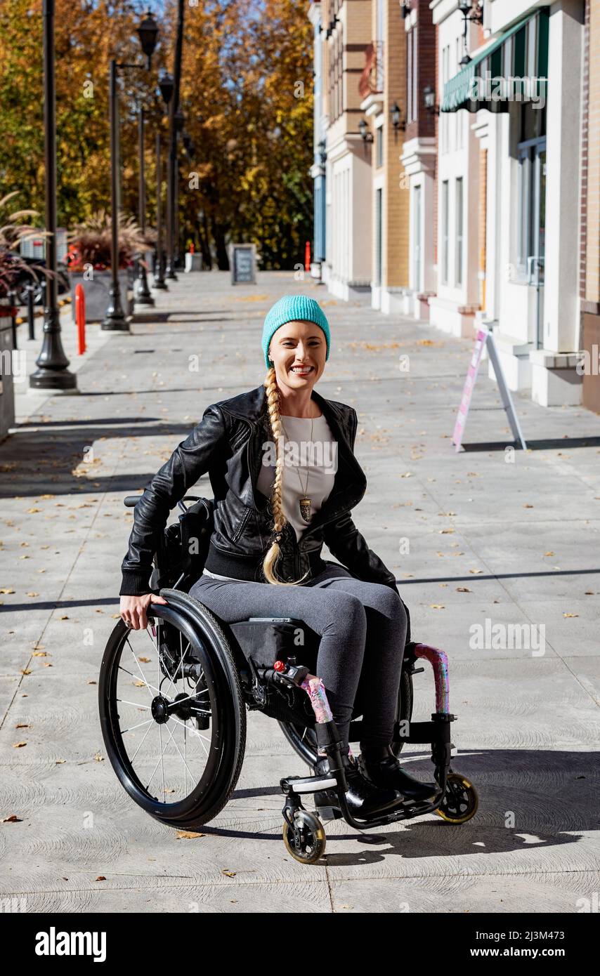 Young paraplegic woman in her wheelchair on a city walkway on a beautiful fall day; Edmonton