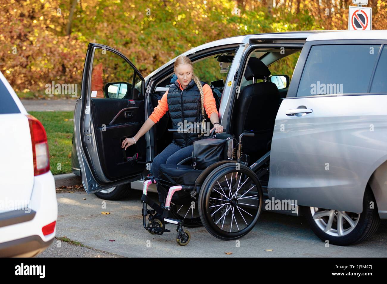 Young paraplegic woman moves from her wheelchair to the driver's seat