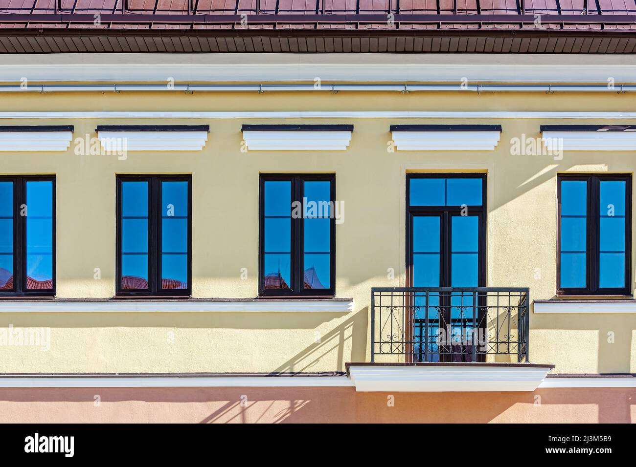 renovated old building facade with rows of windows and balconyю closeup view in sunny day. Stock Photo