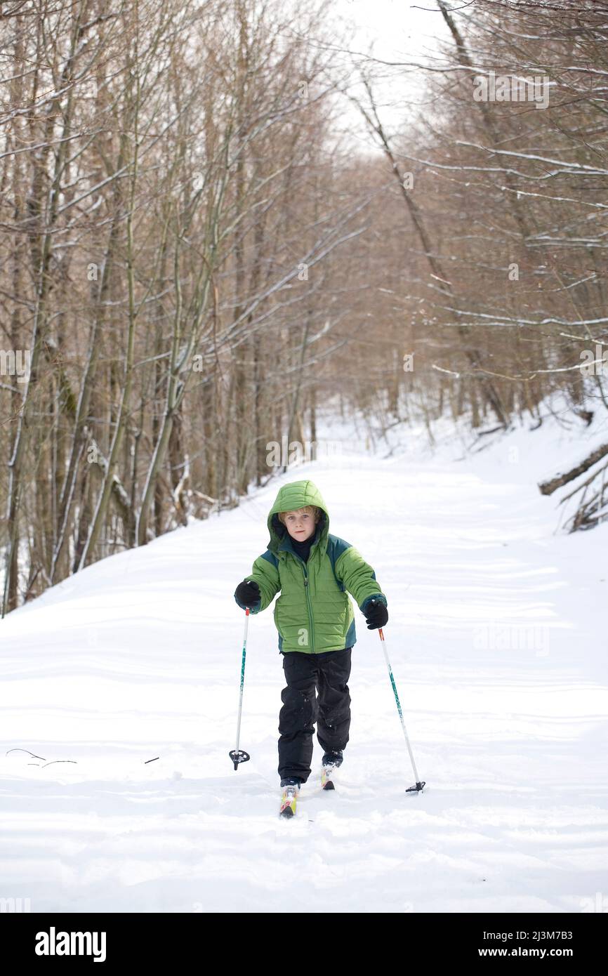 A seven year old boy crosscountry skiing on a snowy road.; Monongehela