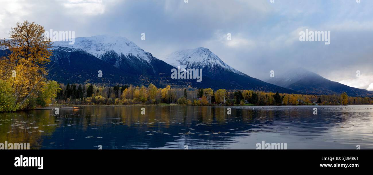 Tranquil Lake Kathlyn surrounded by autumn coloured trees and snow