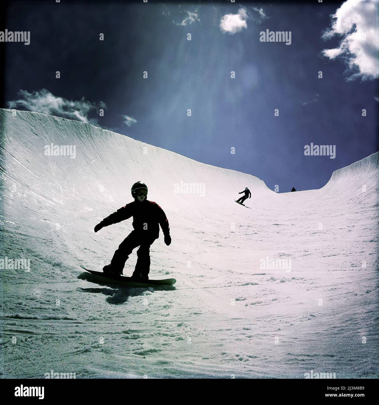 An eleven year old boy and his Mom snowboarding in a large halfpipe